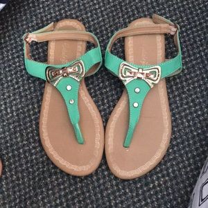 Green sandals with gold bow embellishment